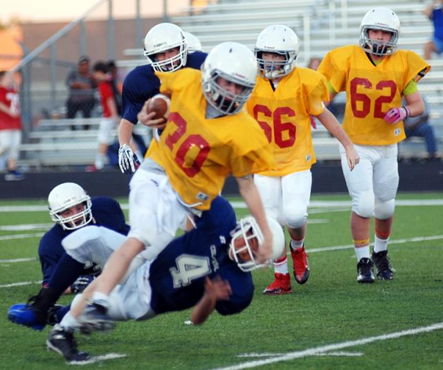 Middle school football running back breaking tackle