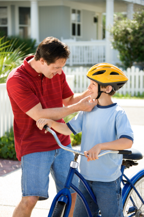 Father adjusting son's bike helmet