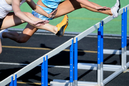 Female hurdlers stretching over hurdle