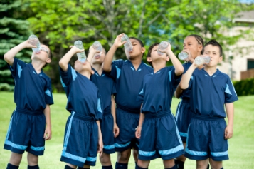 Young male soccer players all drinking water