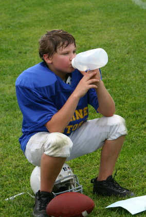 Young football player drinking from water jug