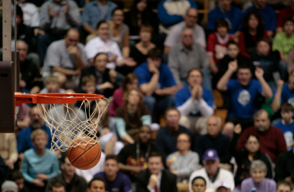 Basketball falling through hoop with crowd in background